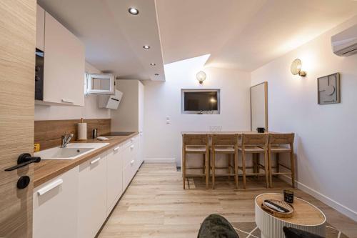 een keuken met witte kasten en een tafel bij MEY T2 - Superbe appartement 4 pers, 50m du vieux port et 2min à pied du palais in Cannes