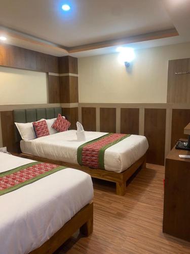 a hotel room with two beds and a desk at Hotel Middle Temple Pvt Ltd in Kathmandu