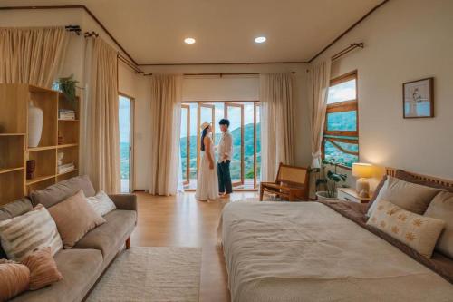 a couple standing in a living room looking out the window at Wintery House in Ban Thung Phan Ha