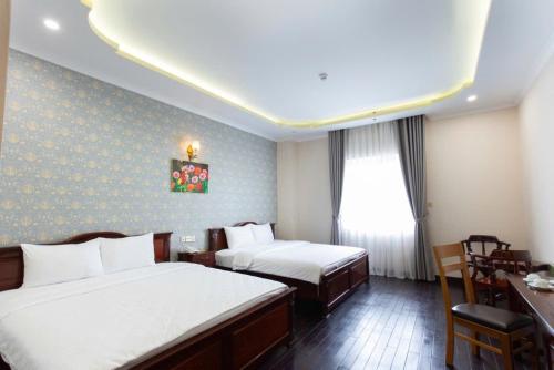 a hotel room with two beds and a desk at Khách Sạn Sunrise Đà Lạt in Ấp Ða Lợi