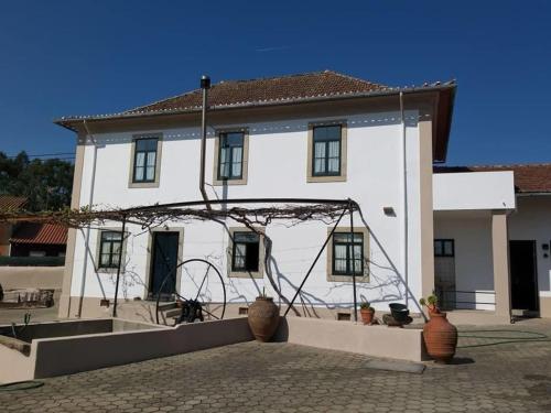 a large white house with a sculpture in front of it at Casa da Carlota in São Vicente de Pereira Jusã