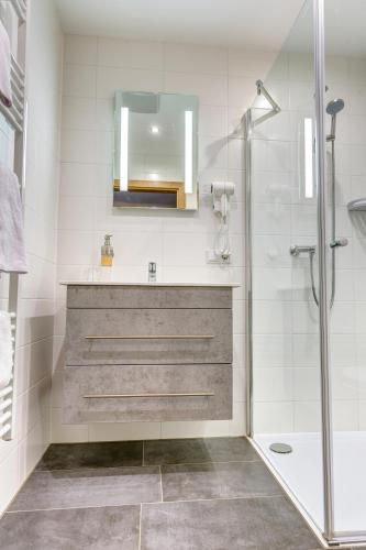 a bathroom with a shower and a sink and a mirror at Smarthotel Schmid in Sitzenberg