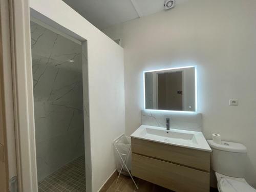 une salle de bain blanche avec un lavabo et un miroir dans l'établissement Juste à côté de la gare de Nîmes, à Nîmes