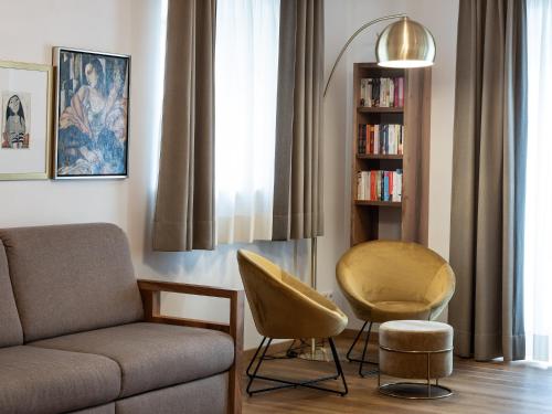 a living room with a couch and a chair and a book shelf at Romantik Hotel Jagdhof in Caldaro