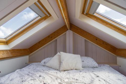 a bed with two pillows in a room with windows at Pat's home in Alkmaar