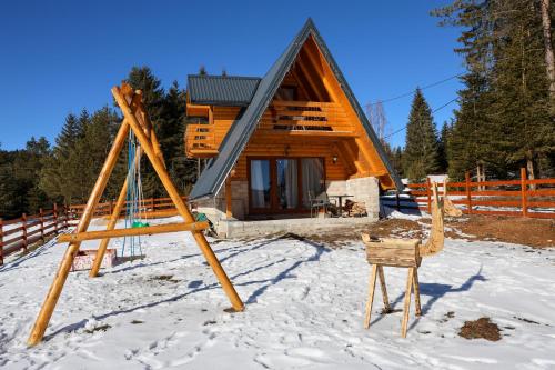 a log cabin in the snow with a chair at Vikendica Monte Pino Romanija in Sokolac