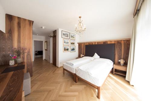 a bedroom with a large white bed and a chandelier at Romantik Hotel Jagdhof in Caldaro