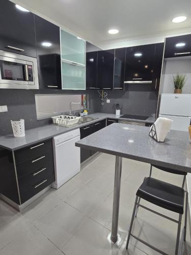 a kitchen with black cabinets and a table and chairs at AL Manas Pereira in Castro Marim