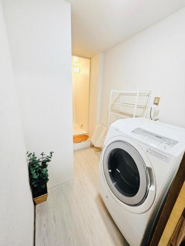 a white washing machine in a room with a plant at 心斎橋から7分 なんばまで1駅 MeenoHome 幸せをひとりじめできる一軒家 空港直通 子ども歓迎 in Osaka