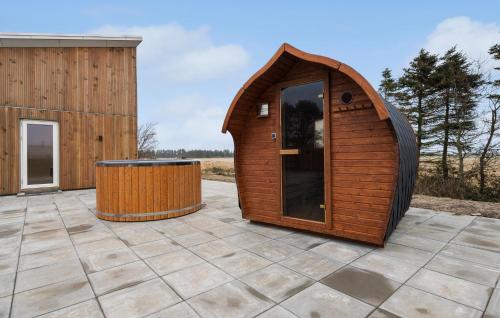 una casa de perros de madera en un patio con un barril en Beautiful Home In Ulfborg With Sauna, en Ulfborg