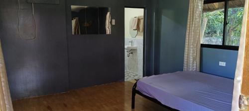 a bedroom with a purple bed and a bathroom at Hidden Paraiso Resort in Puerto Galera