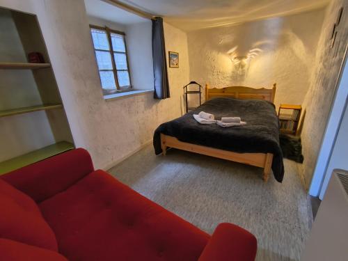 - une chambre avec un lit et un canapé rouge dans l'établissement Maison authentique avec jardin, à Briançon