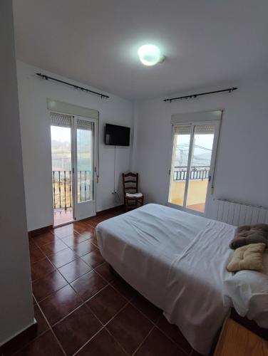 a bedroom with a large bed and a balcony at H Helechosa in Helechosa