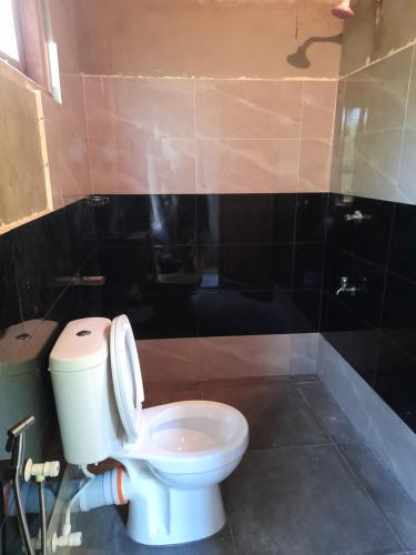 a bathroom with a white toilet in a room at Rustic Campsite Kalutara South in Kalutara