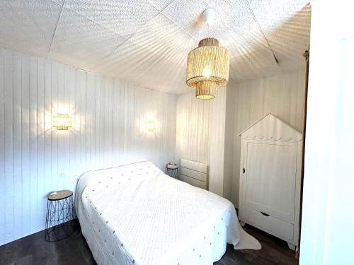 - une chambre blanche avec un lit blanc et un lustre dans l'établissement Maison 3 pièces - véranda - 4 personnes - Proche plage - ANDREA, à Ploemeur