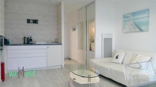 un salon avec un canapé blanc et une table en verre dans l'établissement Ocean vert - front de mer - balcon, à La Baule