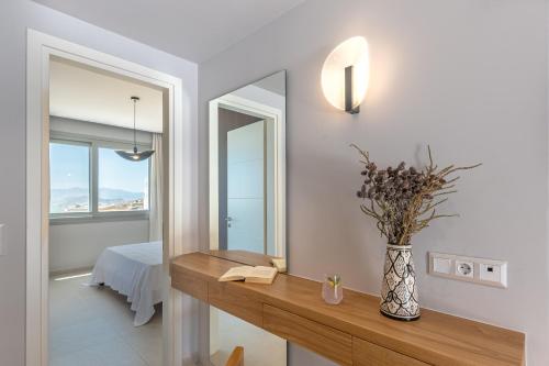 a bathroom with a mirror and a vase with flowers on a counter at Eartha Horizon Villas Naxos in Naxos Chora