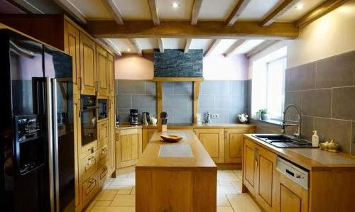 a large kitchen with wooden cabinets and a black refrigerator at Gîte "L'échappée amoureuse et féérique" in Paliseul