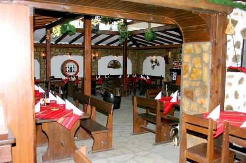 un restaurante con mesas de madera y sillas con servilletas rojas en Family House Oreha, en Bansko