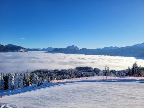 a view of a snow covered hill with a view of the clouds at Alpenhaus Dachstein.Zauber in Abtenau