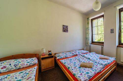 a bedroom with two beds and a desk and two windows at Penzion Šumavous in Vimperk