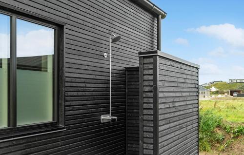 a black house with a window and a shower at Awesome Home In Løkken With Sauna in Løkken