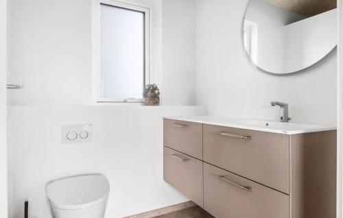 a bathroom with a sink and a toilet and a mirror at Awesome Home In Løkken With Sauna in Løkken
