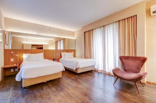 a hotel room with two beds and a chair at Radisson Blu São Paulo in Sao Paulo