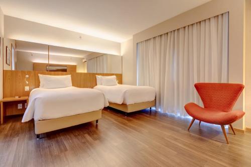 a hotel room with two beds and a chair at Radisson Blu São Paulo in Sao Paulo