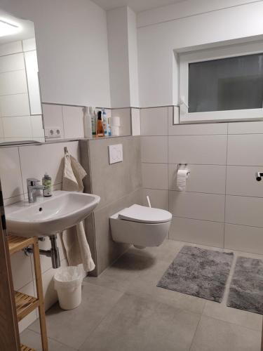 a white bathroom with a sink and a toilet at Ferienwohnungen Meyer in Heilsbronn