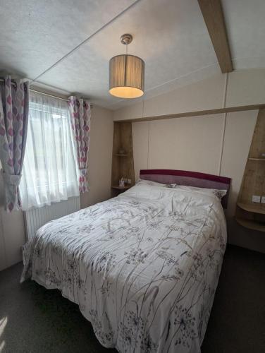 a bedroom with a bed with a white comforter at BRIGHT and COMFORTABLE HOLIDAY HOME SWANAGE BAYVIEW HOLIDAY PARK in Swanage
