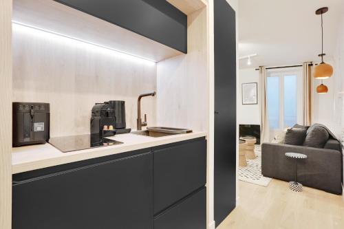 - une cuisine avec des placards noirs, un évier et un canapé dans l'établissement Au coeur du sacré coeur, à Paris