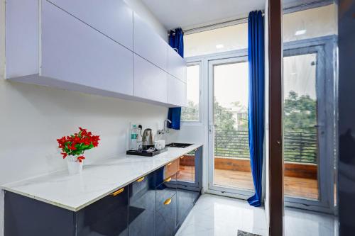 a kitchen with white cabinets and a large window at Limewood Stay - Sector 29 Gurgaon in Gurgaon