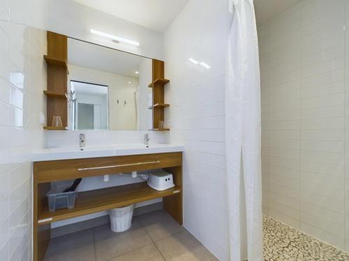 une salle de bain avec un lavabo et un miroir dans l'établissement Sur la plage, appartement avec terrasse et vue mer, à La Tranche-sur-Mer