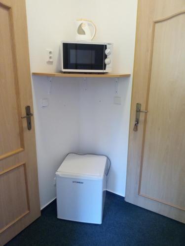 a room with a trash can and a microwave on a shelf at Penzion Šumavous in Vimperk