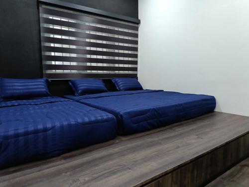 a bed with blue pillows on a wooden platform at Newstar Jacuzzi Homestay Near Jonker Kota Laksamana Melaka in Melaka