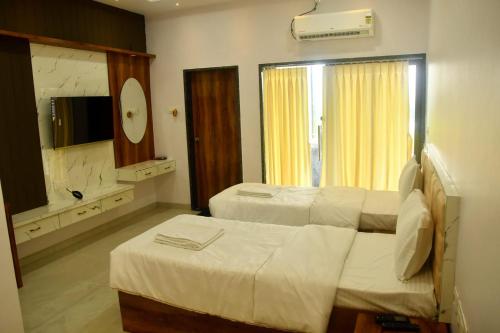 a hotel room with two beds and a mirror at Ajanta hill resort fardapur in Phardāpur