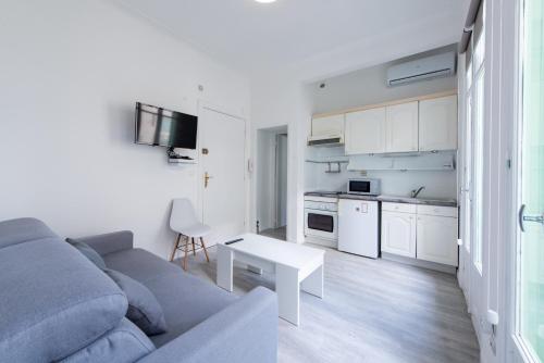 Il comprend un salon avec un canapé gris et une cuisine blanche. dans l'établissement Happyfew Le Miramar, à Nice
