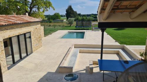 Elle offre une vue sur une terrasse avec une piscine. dans l'établissement MAGNIFIQUE Mas, à Orange