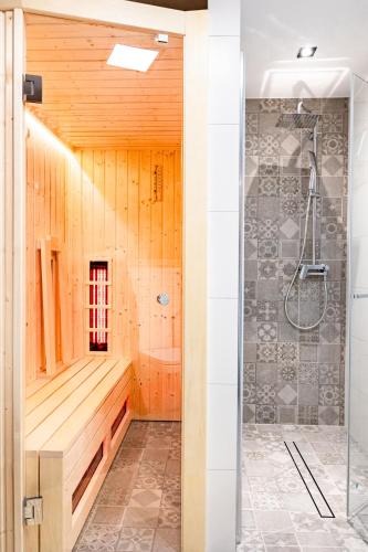 a bathroom with a shower with a wooden wall at Dom nad Potokiem z sauną in Lipowa