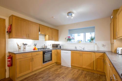 a large kitchen with wooden cabinets and a window at Honeybee Cottage in Penrith