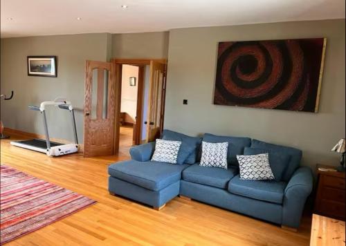 a living room with a blue couch and a treadmill at The Roundhouse in Lettermullan