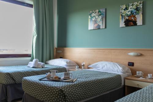 a hotel room with two beds and a tray of food at Hotel Ayri in Medesano