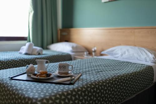 a tray with a plate of food on a bed at Hotel Ayri in Medesano