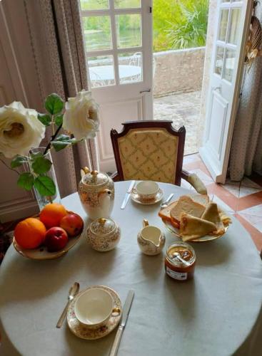 une table avec des fruits et des assiettes et un vase avec des roses dans l'établissement Le Galet, à Saint-Dyé-sur-Loire