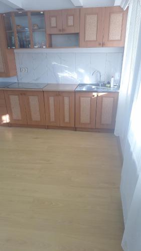an empty kitchen with a sink and wooden cabinets at Tskaltubo-house in Tskaltubo