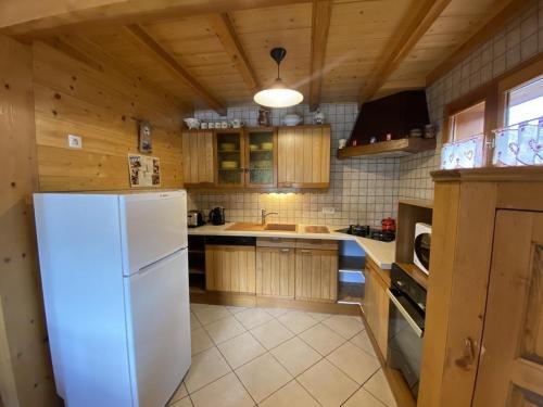 a kitchen with a white refrigerator and wooden cabinets at Chalet Le Castor : dans le centre de Chatel in Châtel