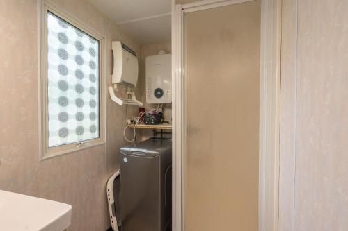 una pequeña cocina con nevera y ventana en Mobilhome Mh75 La Tremblade, en La Tremblade