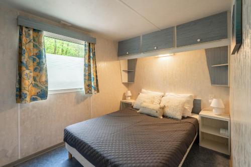 Un dormitorio pequeño con una cama y una ventana. en Mobilhome Mh75 La Tremblade, en La Tremblade