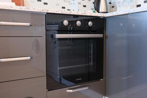 a black oven in a kitchen with grey cabinets at Şahin Tepesi Suite Otel in Trabzon